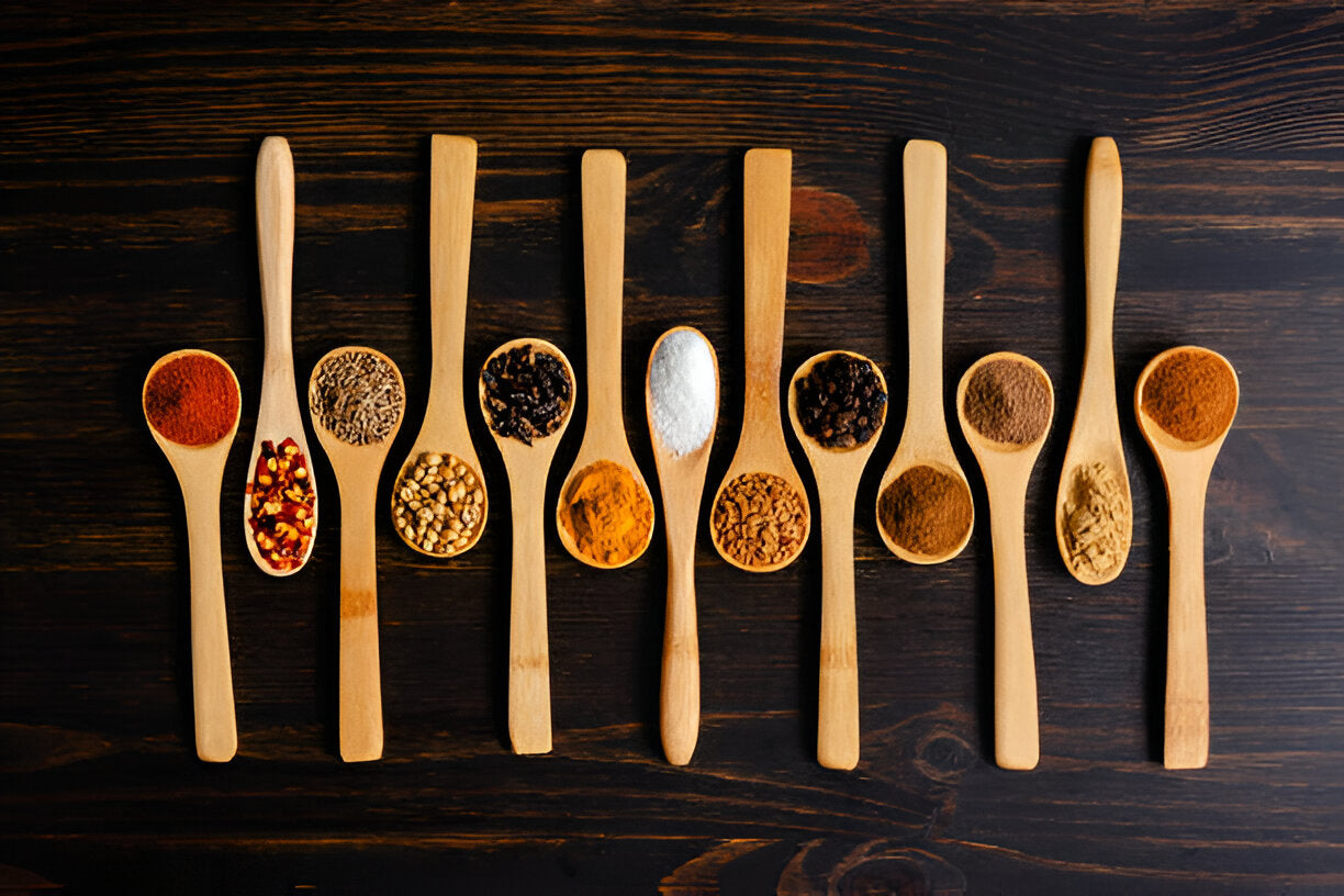 A vibrant flat lay of turmeric, cinnamon sticks, black peppercorns, and cloves on a rustic table