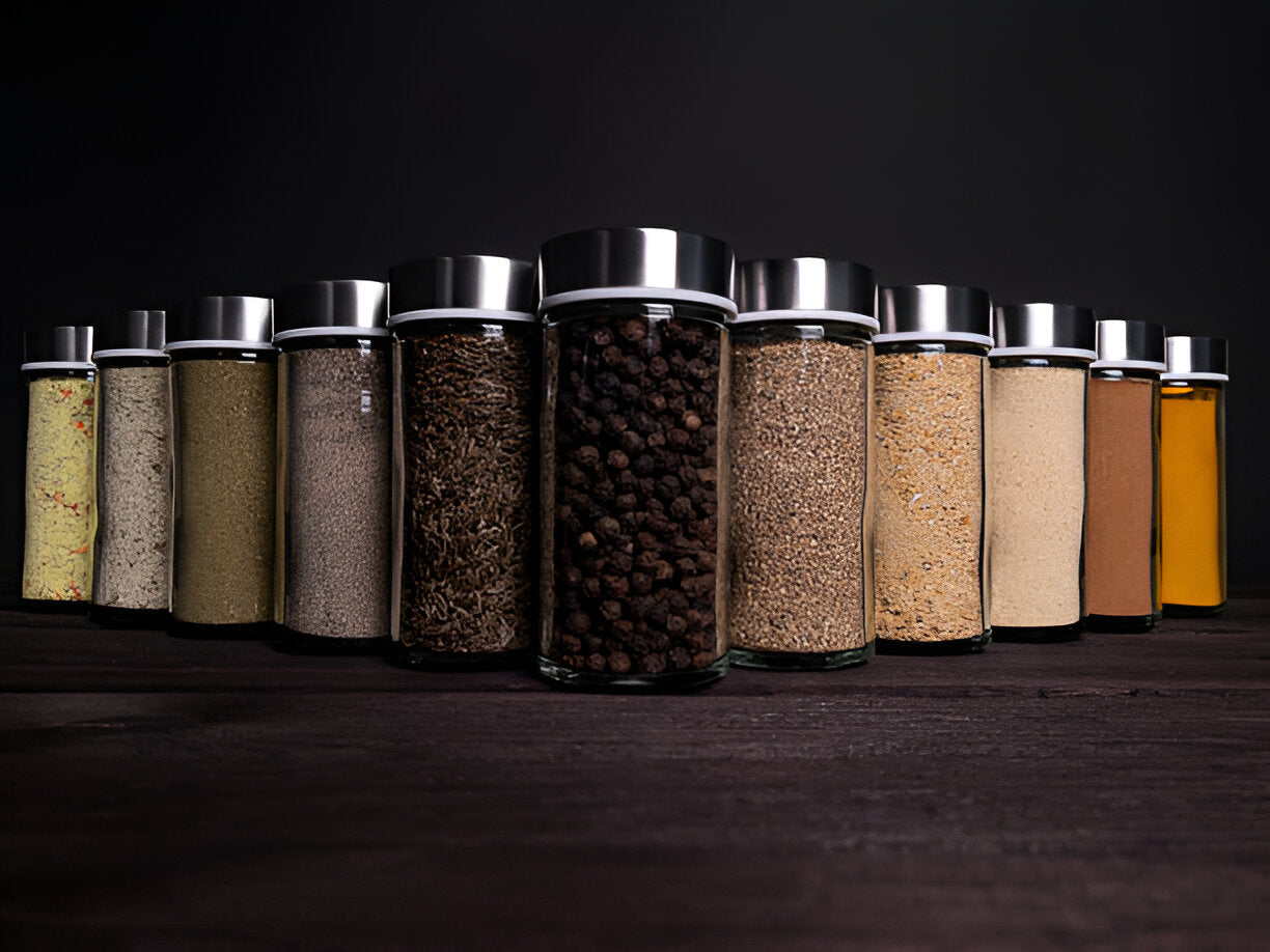 Ten essential spices arranged in clear jars on a wooden spice rack in a bright kitchen